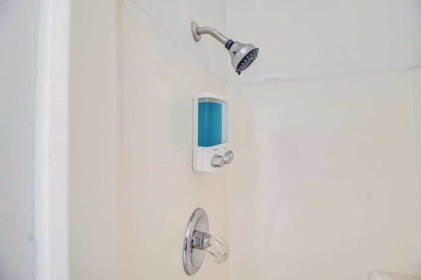 A shower with a handheld showerhead and a control panel.