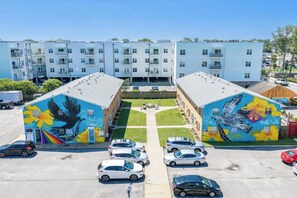 A multi-story building with a parking lot in front. - Oceanfront 2BR • Walk to Atlantic Park (Virginia Beach)