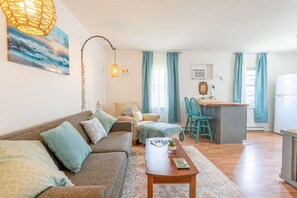 A cozy living room with a sofa, a coffee table, and a dining area with chairs. - Quiet 2BR • Walk to Beach, ViBe & The Dome (Virginia Beach)