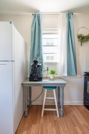 A compact kitchenette with a coffee maker, a small potted plant, and a window with curtains. - Quiet 2BR • Walk to Beach, ViBe & The Dome (Virginia Beach)