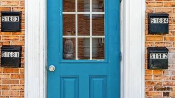 Une porte bleue avec un cadre blanc, une boîte aux lettres portant l’inscription « 516B », et un mur de briques.