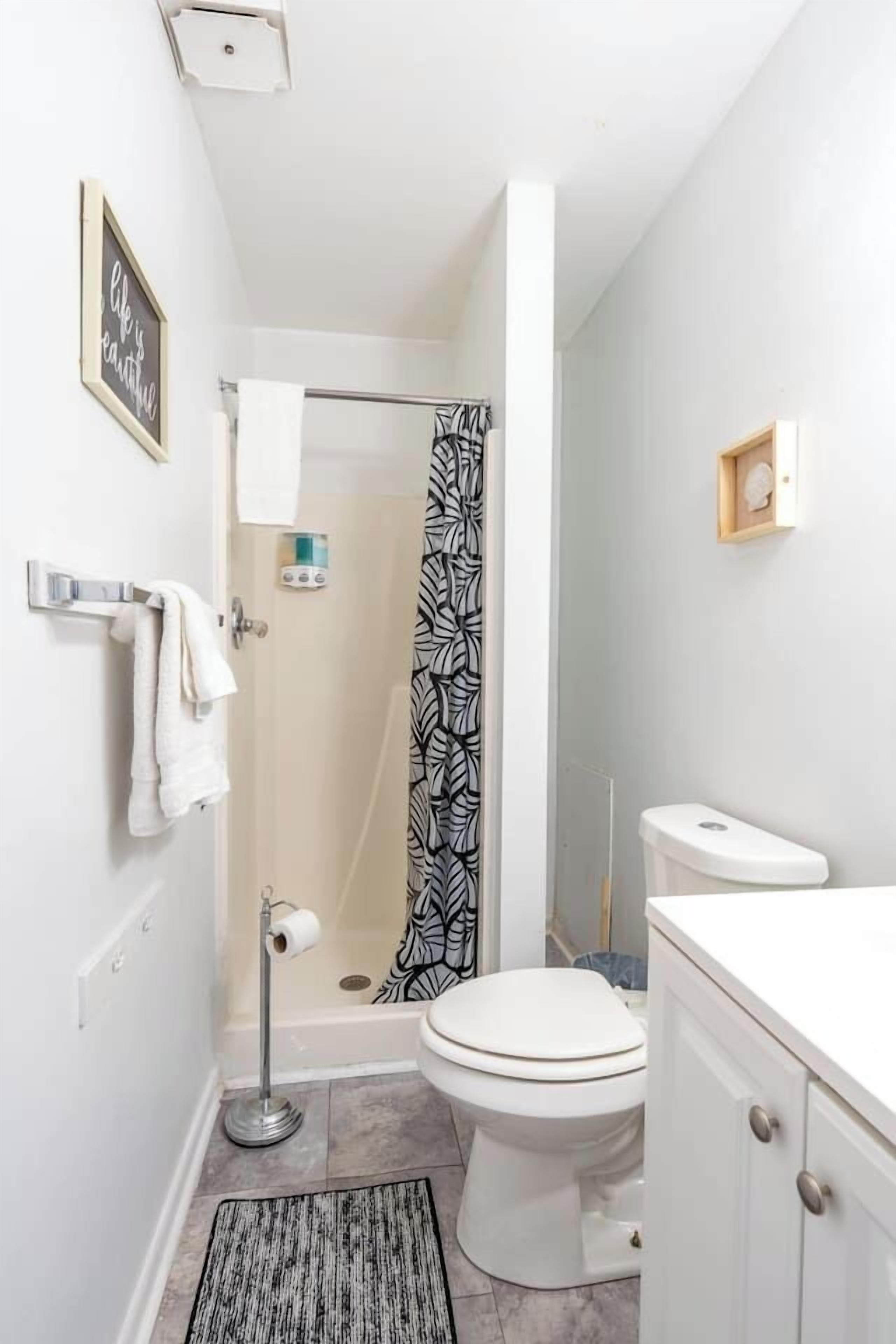 A bathroom with a shower, toilet, and a towel rack.