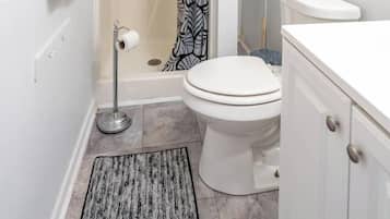 A bathroom with a shower, toilet, and a towel rack.