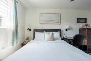 A hotel room with a bed, bedside lamps, a desk with a chair, a globe, and a motivational sign. - Economy 2BR • Walk to Beach & Atlantic Park (Virginia Beach)