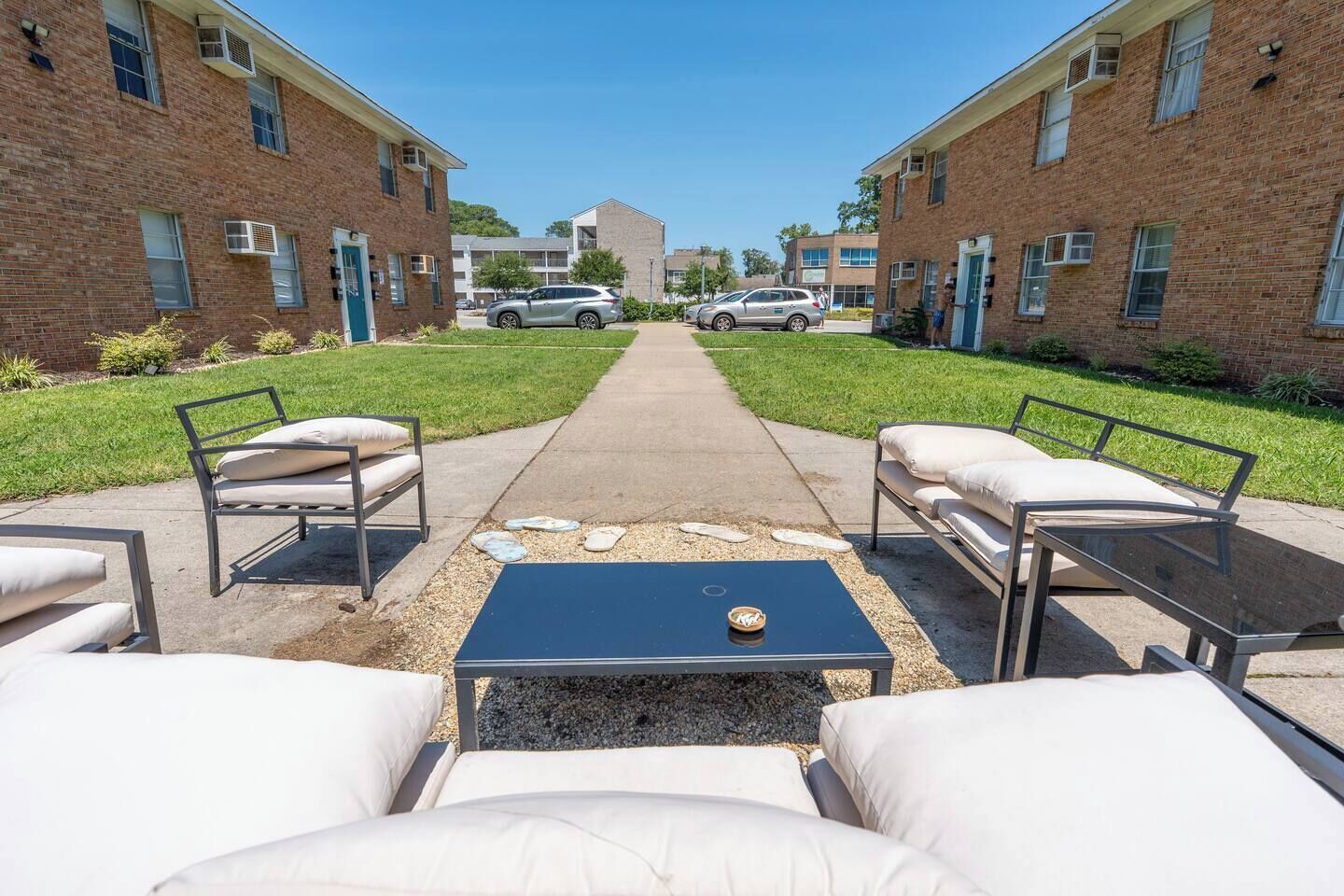 Un patio con mesas al aire libre, un sendero y un edificio al fondo.