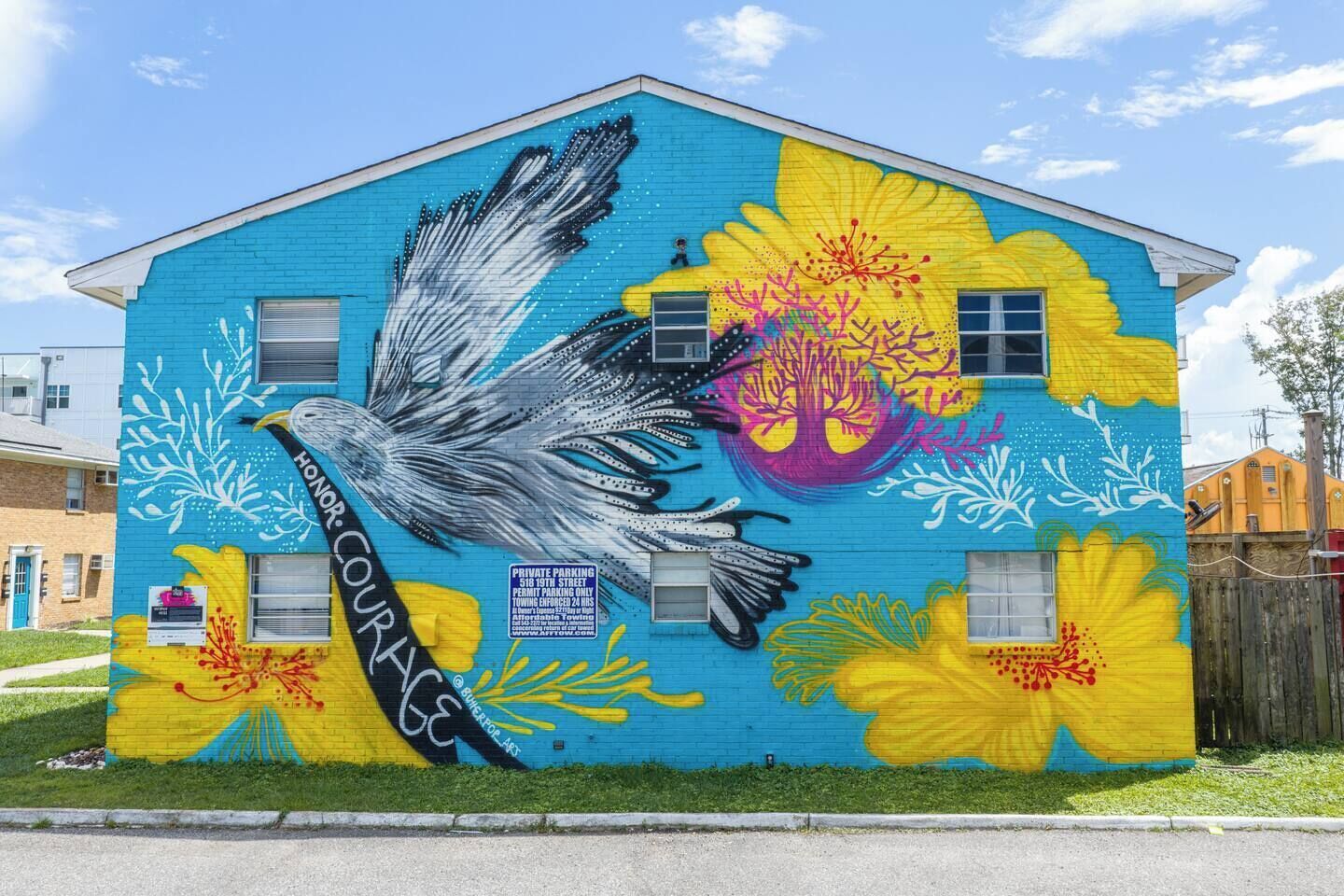 Un edificio con un mural colorido que muestra un ave y flores.
