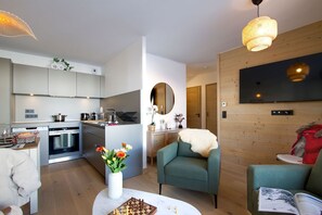 A modern apartment with a kitchen, living area, and a dining space. - Ski aux pieds | Vue imprenable | Piscine & Spa (Alpe d'Huez)