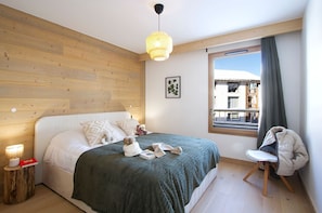Ein Schlafzimmer mit Bett, Nachttischlampe, einem Fenster mit Aussicht und einem Sessel.