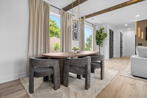 A dining area with a round table, four chairs, and a chandelier. - NEW Luxury home with rooftop hot tub and spa like bathroom (Nashville)