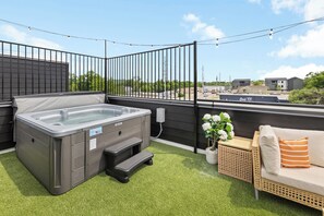A rooftop patio with a hot tub, a wicker sofa, and a string of lights. - NEW Luxury home with rooftop hot tub and spa like bathroom (Nashville)