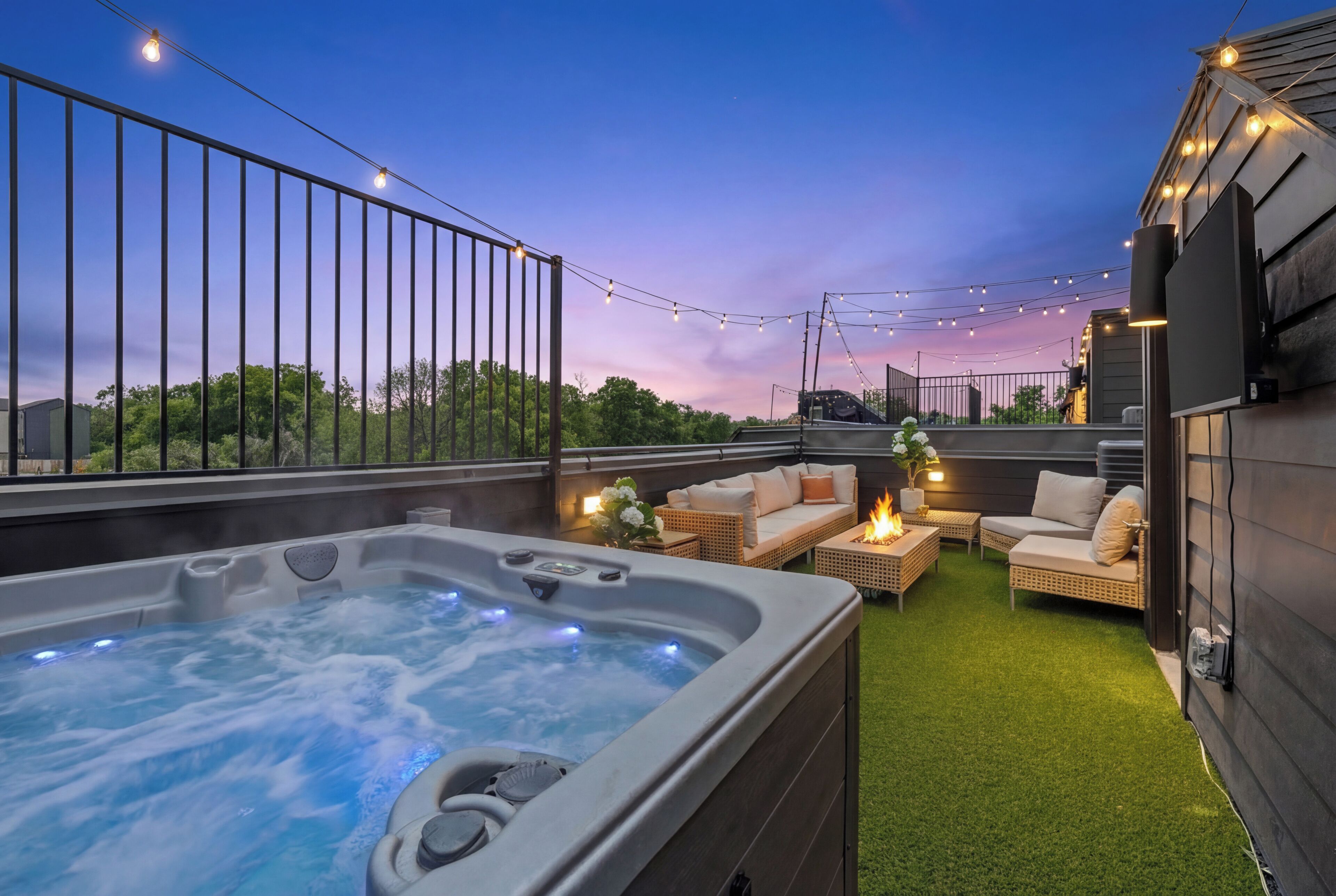 Terraza en la azotea con jacuzzi, mobiliario exterior, luces colgantes y vista al cielo.