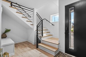 A staircase with wooden steps and black metal railings, leading to a room with a white wall and a door. - NEW Luxury home with rooftop hot tub and spa like bathroom (Nashville)