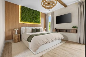 Ein modernes Schlafzimmer mit einem großen Bett, einem an der Wand befestigten Fernseher und einem vertikalen Grünbereich.