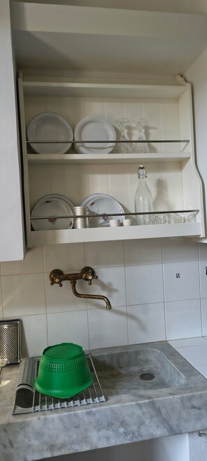 A kitchen with a white cabinet, a green colander, and a stainless steel sink. - Holiday Home 'Tosca' with Wi-Fi (Castiglione di Garfagnana)