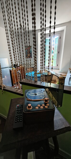 A room with a table featuring a vintage radio and remote control, a hanging bead curtain, and a window with blinds. - Holiday Home 'Tosca' with Wi-Fi (Castiglione di Garfagnana)