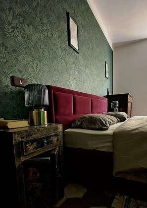 A bedroom with a red headboard, a bedside table with a lamp, and a bed with pillows. - Holiday Home 'Tosca' with Wi-Fi (Castiglione di Garfagnana)