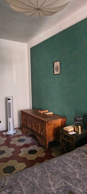 Une pièce avec un mur vert, un bureau en bois, un radiateur et un tapis à motifs.