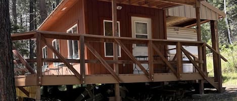 Una cabaña de madera con terraza, rodeada de árboles.