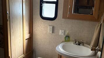 A compact bathroom with a toilet, a sink, and wooden cabinets.