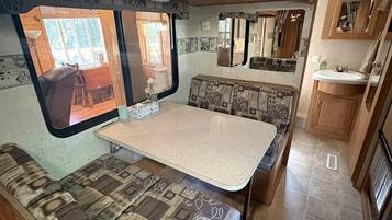 A compact RV interior with a kitchenette, a dining area, and a seating space.