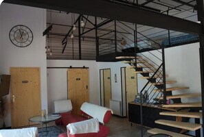 Ein Zimmer mit Treppe, einer Uhr und einem kleinen Tisch.