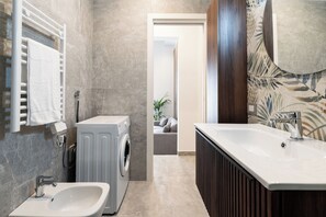 Un baño moderno con lavadora incorporada, lavamanos y un espejo grande.