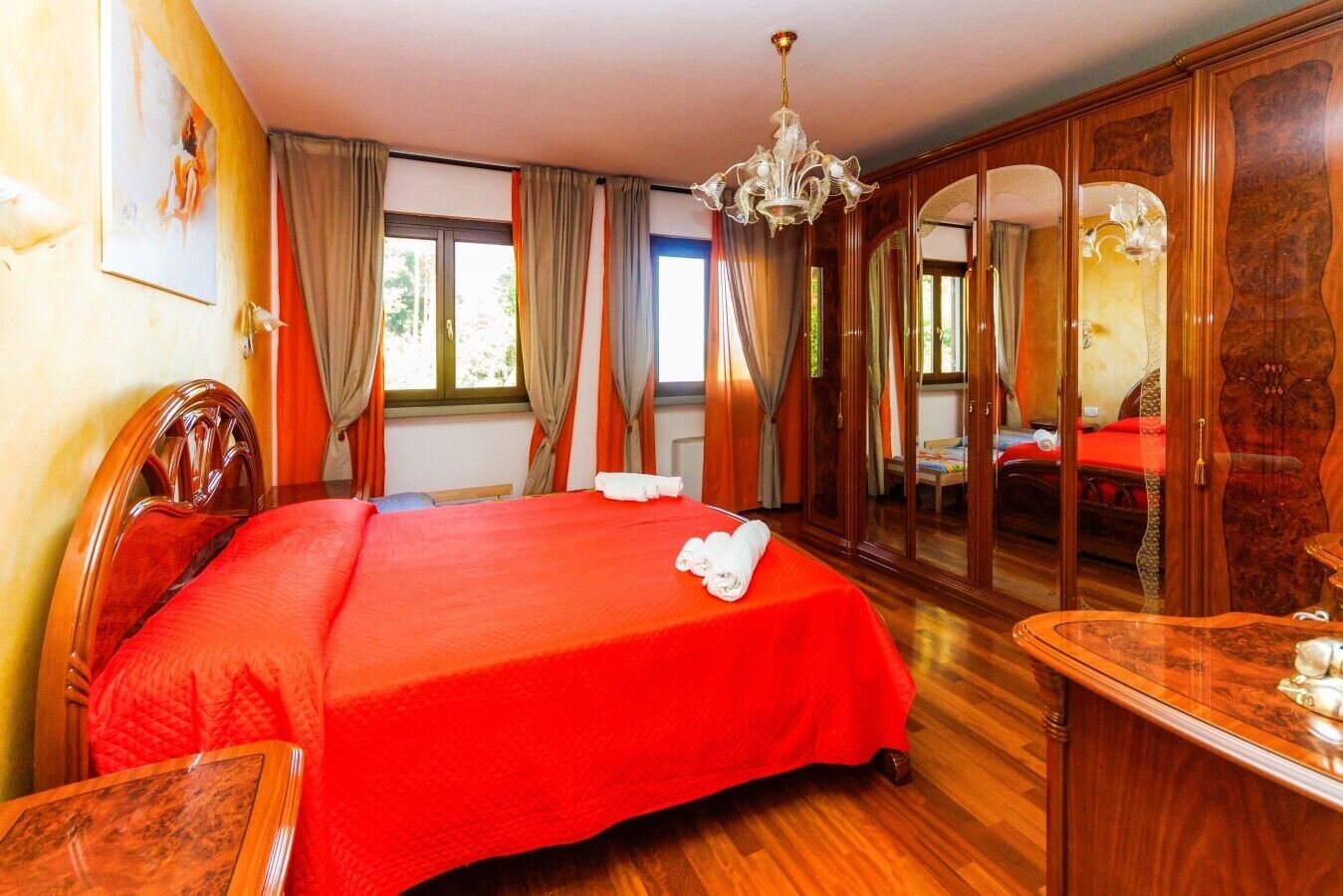 Una camera d'albergo con un letto grande, mobili in legno, un lampadario e uno specchio.