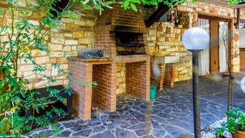 Une terrasse en pierre avec une cuisine extérieure en briques et un lampadaire.