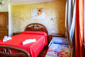 Une chambre d’hôtel avec un lit en bois, une couvre-lit rouge, un tableau au mur et une petite table de chevet.