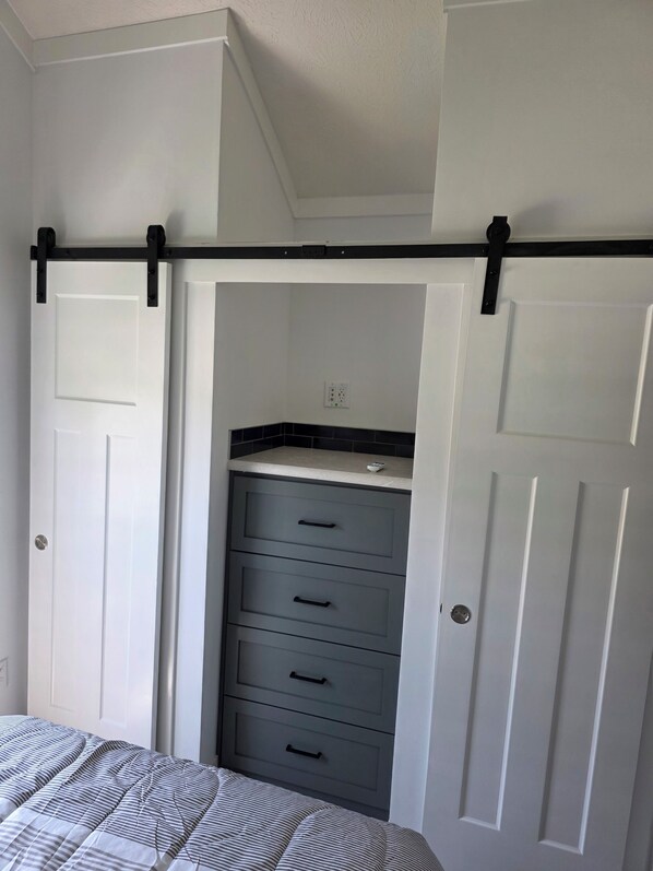 A bedroom with a bed, a closet with sliding doors, and a dresser. - Luxury Tiny Living: Brand New Waterfront Escape (Havelock)