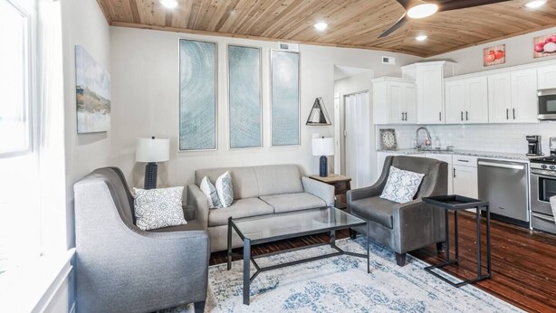 A modern living room with a grey sofa, a coffee table, and a ceiling fan. - 3BR | Steps to Beach & Boardwalk (Atlantic City)