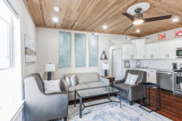A modern living room with a grey sofa, a coffee table, and a ceiling fan. - 3BR | Steps to Beach & Boardwalk (Atlantic City)