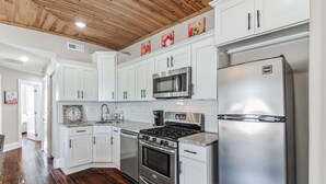 A kitchen with white cabinets, stainless steel appliances, a wooden ceiling, and a granite countertop. - 3BR | Steps to Beach & Boardwalk (Atlantic City)