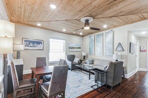 A spacious living area with a wooden ceiling, a dining table with chairs, a sofa, and a coffee table. - 3BR | Steps to Beach & Boardwalk (Atlantic City)