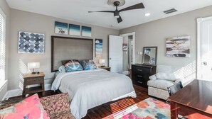 A bedroom with a bed, bedside tables, a dresser, a chair, and artwork on the walls. - 3BR | Steps to Beach & Boardwalk (Atlantic City)