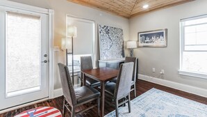 A dining area with a wooden table and chairs, a cityscape painting, and a cityscape photograph on the wall. - 3BR | Steps to Beach & Boardwalk (Atlantic City)
