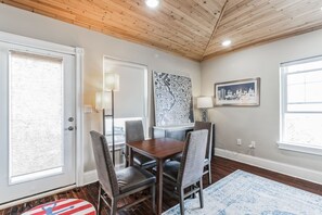 A dining area with a wooden table and chairs, a cityscape painting, and a cityscape photograph on the wall. - 3BR | Steps to Beach & Boardwalk (Atlantic City)