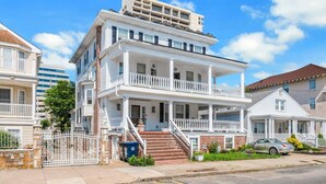 A multi-story residential building with a front porch, a staircase, and a gated entrance. - 3BR | Steps to Beach & Boardwalk (Atlantic City)