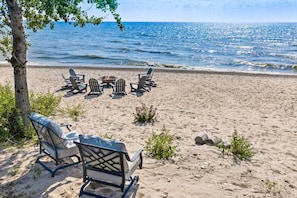 Una playa con un brasero y sillas Adirondack.