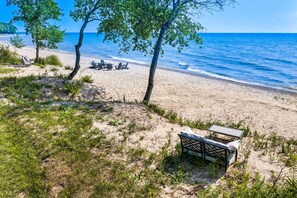Una spiaggia con una panchina, lettini e un tavolo.