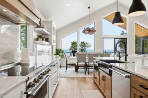 Una cocina moderna con una isla grande, electrodomésticos integrados y vistas al océano.