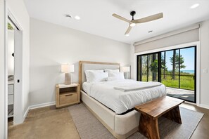 Una camera da letto moderna con un letto grande, comodini, una ventola a soffitto e vista sull'esterno.