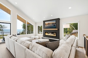 A modern living room with a large sofa, a fireplace, and a television mounted on the wall.