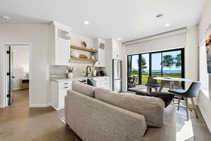 A modern kitchen with white cabinetry, a marble countertop, and a built-in refrigerator.
