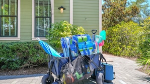 A cart loaded with various items including a blue umbrella, a black bag, and cleaning supplies. - The Summer Sweet Escape by Stay on 30a (Santa Rosa Beach)