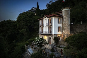 A two-story building with a stone tower, surrounded by lush greenery and a clear sky. - Villa La Solitaria - My Home in Como (Blevio)