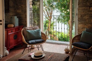 A room with wicker chairs, a red cabinet, and a view of greenery through a glass door. - Villa La Solitaria - My Home in Como (Blevio)