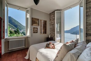 A bedroom with a bed, a window with a mountain view, and a radiator. - Villa La Solitaria - My Home in Como (Blevio)