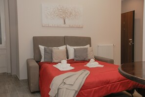Ein Hotelzimmer mit einem Bett, einem kleinen Tisch, einem Heizkörper und einer Tür.
