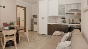 Una cocina moderna con gabinetes blancos, horno empotrado y zona de comedor con mesa y sillas.